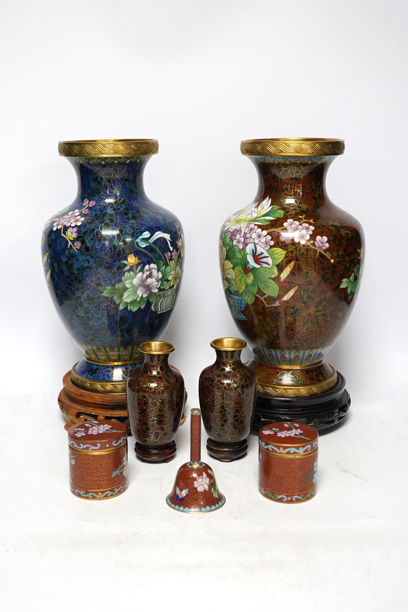 Two large Chinese cloisonné vases with hardwood stands, a smaller pair of vases, a pair of similar boxes and covers and a small table bell, tallest 31cm. Condition - fair to good